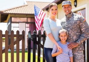 military family outside house with American falg