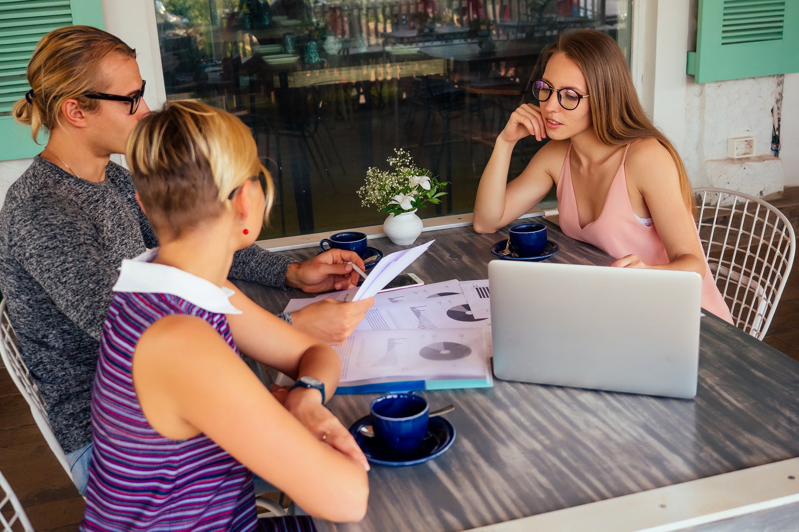 Business Team Meeting. Successful Business Partners Working Toge Business team meeting. Successful business partners working together with laptop, while sitting in urban summer cafe outdoors.freelancer distant remote work teamwork