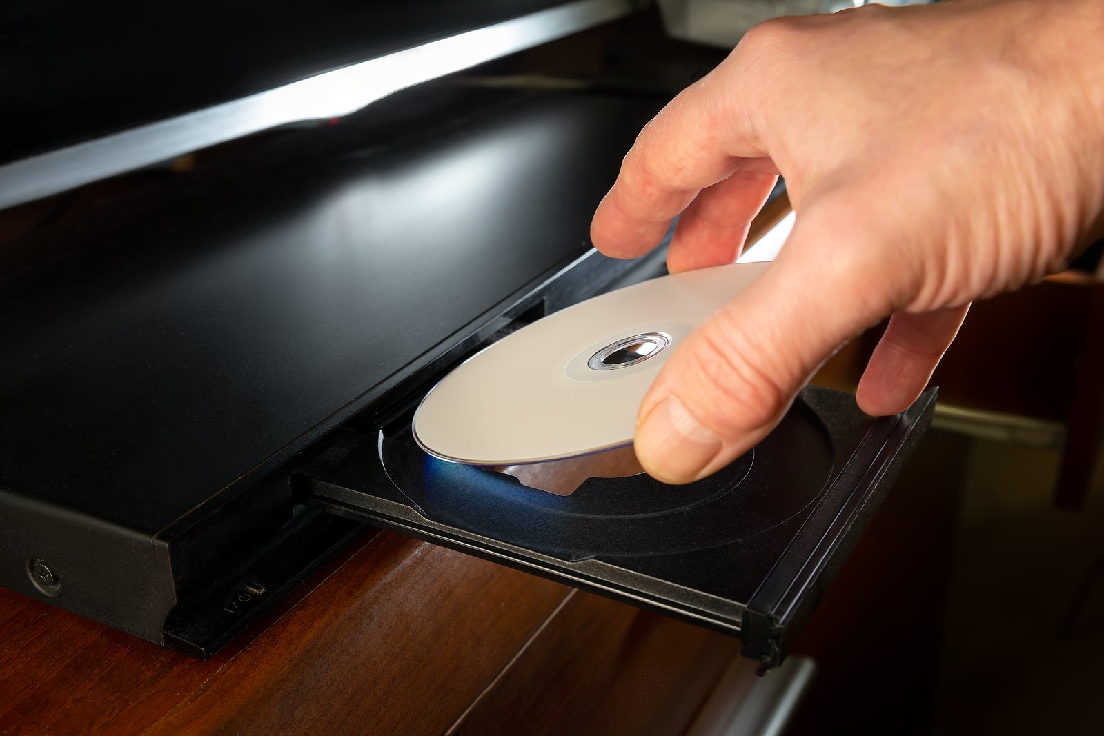 hand holding dvd-disk insert to dvd player