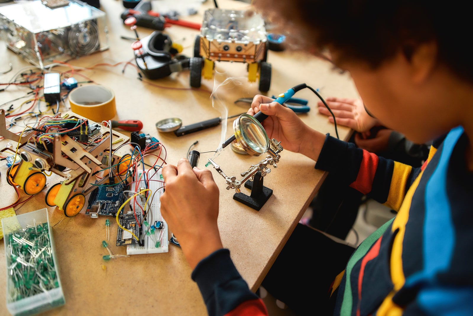 Young engineer using soldering iron to join chips and wires. Robotics and software engineering for elementary students. Inventions and creativity for kids. Tinkering, educational activities concept.