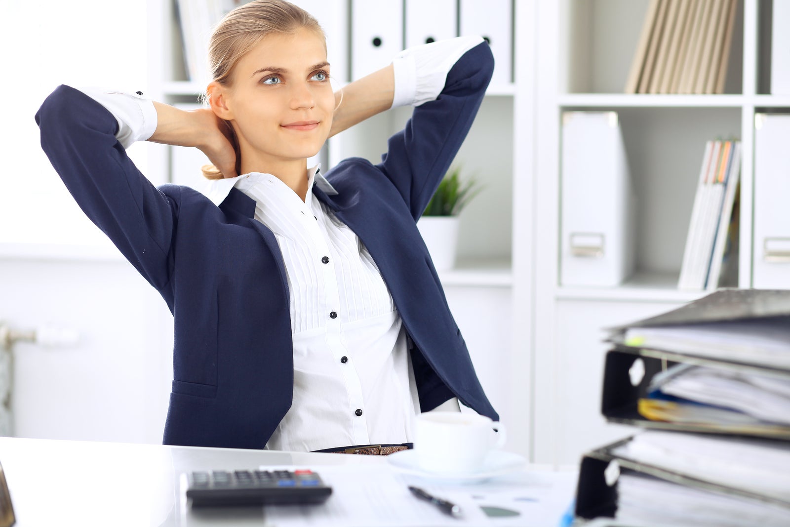 Happy business woman or female accountant having some minutes for coffee and pleasure at working place.