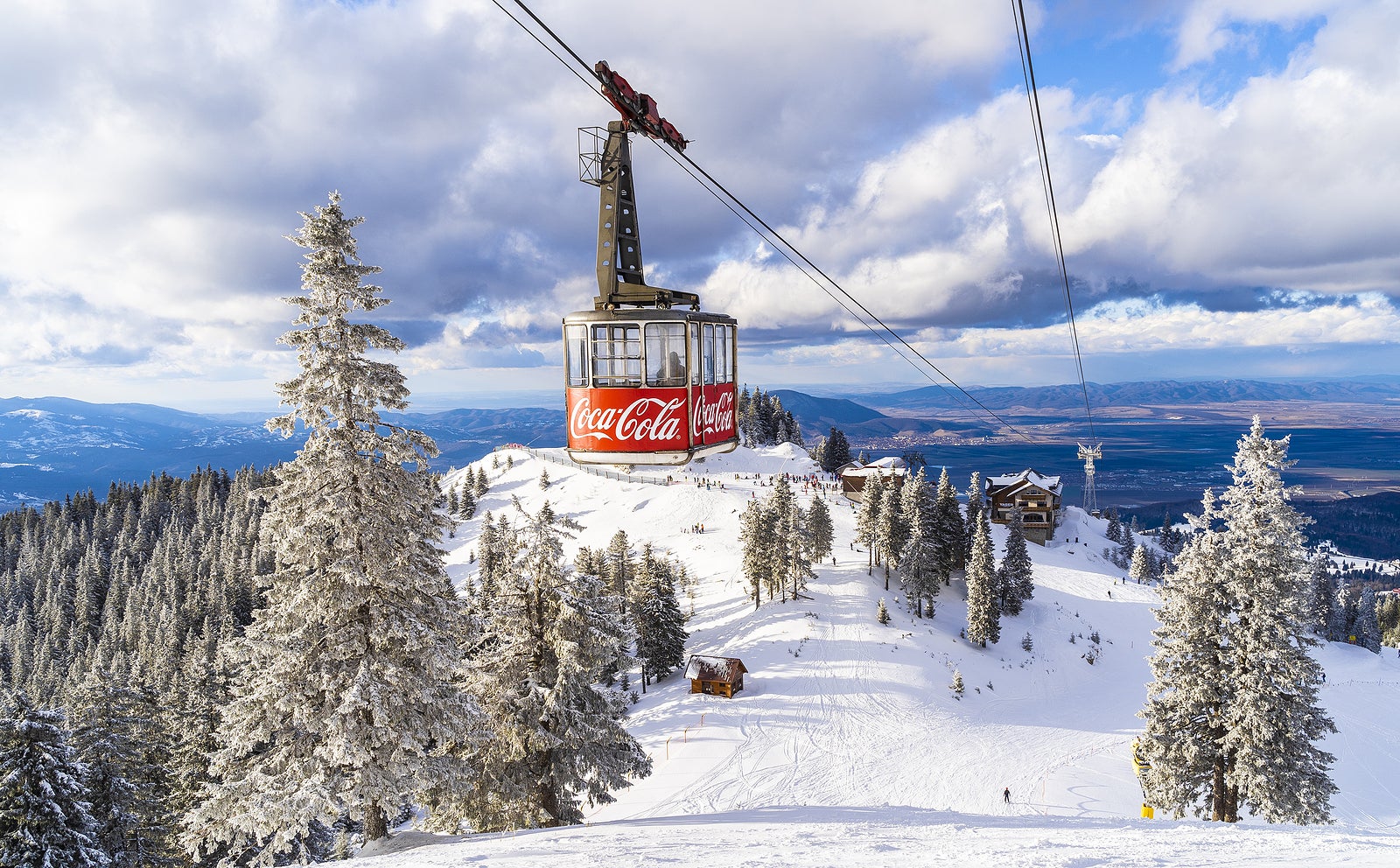 Brasov, Romania - February 12, 2020: Aerial view of the famous ski slope in Poiana Brasov  with greatest Coca Cola company imprinted on cable car reaching high altitude