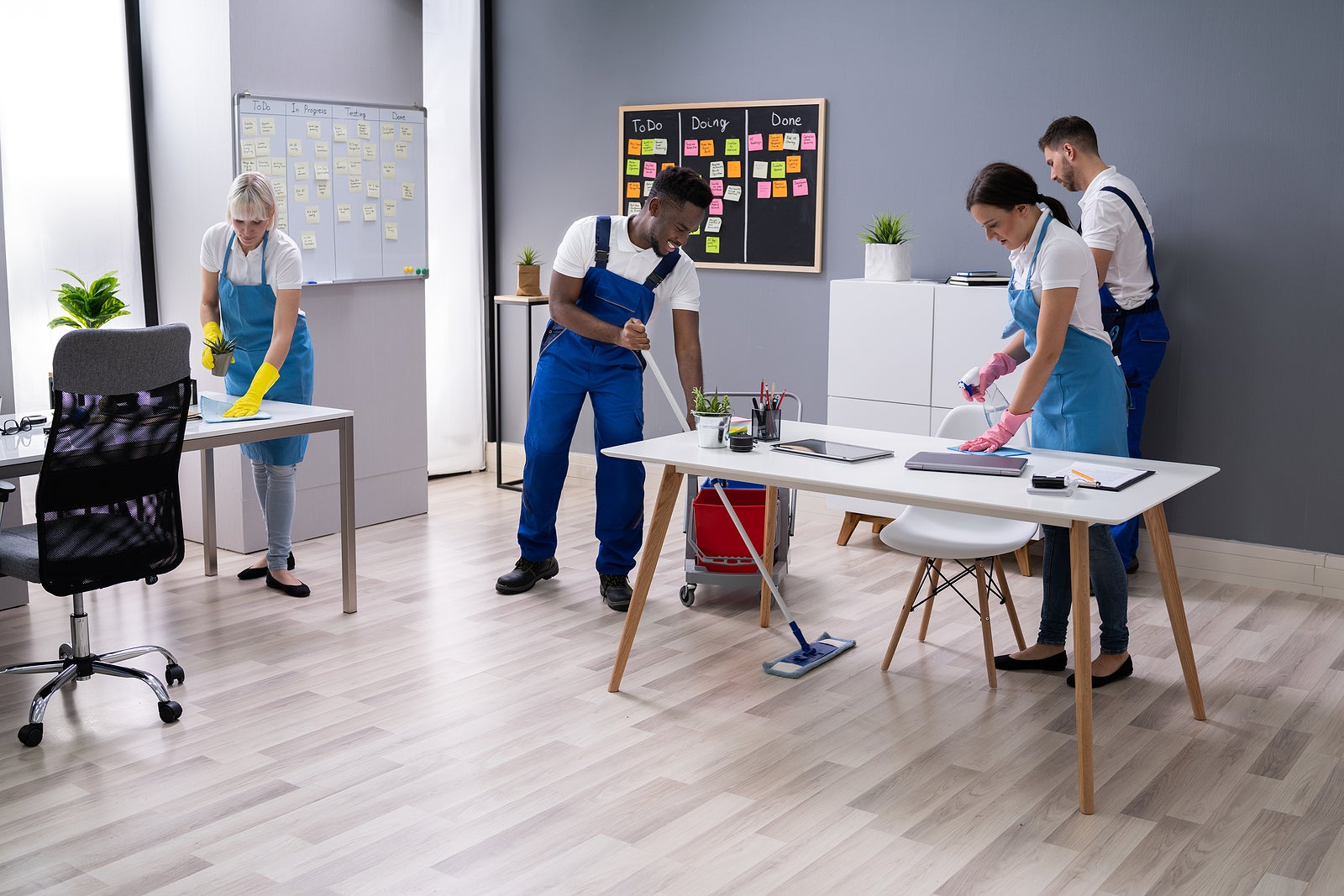 Group Of Janitors In Uniform Cleaning The Office With Cleaning Equipment