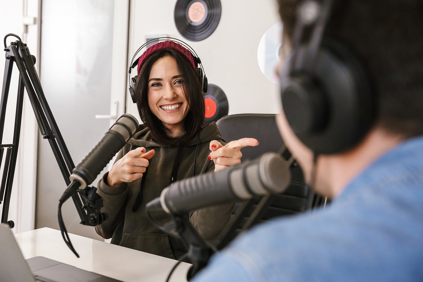 Man and woman in white shirts podcasters interview each other for radio podcast