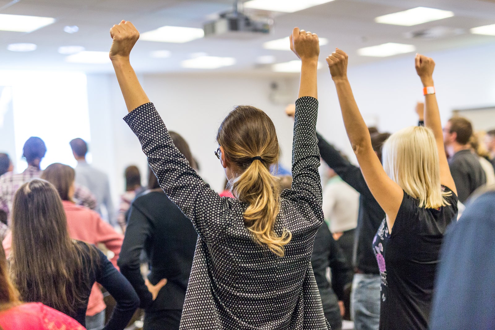 Participants of interactive motivational speech feeling empowered and motivated, hands raised high in the air.