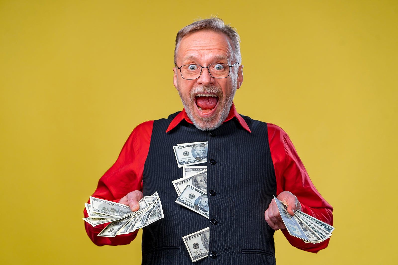 Portrait of super excited senior mature man who just won lots of money, trying to give money to the camera, isolated on yellow background. Positive emotion facial expression feelings. Closeup