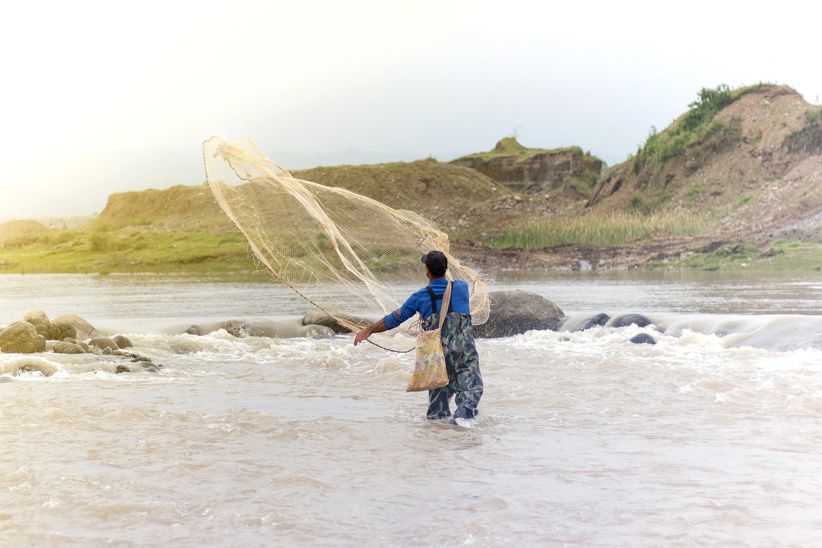 Throwing fishing net. Photo shot of water spatter from fisherman while throwing fishing net on the river.