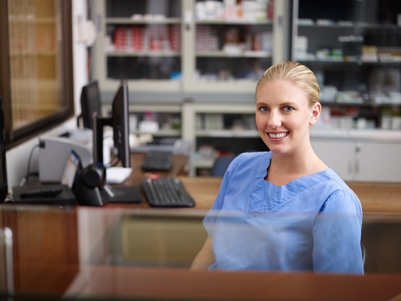 Young woman at work as receptionist and nurse in hospital looking at camera