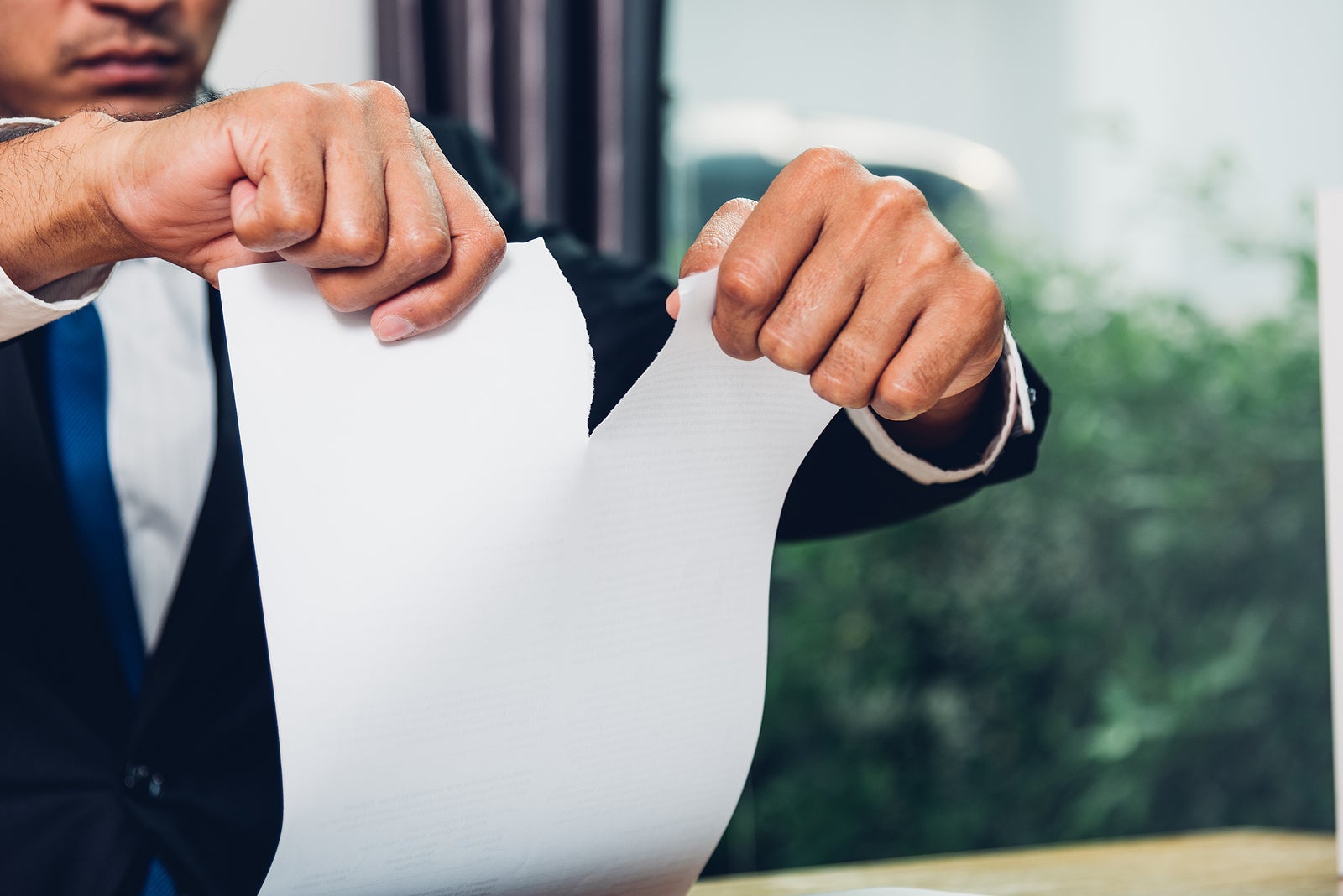 Business man angry breaking tearing paper document on desk office