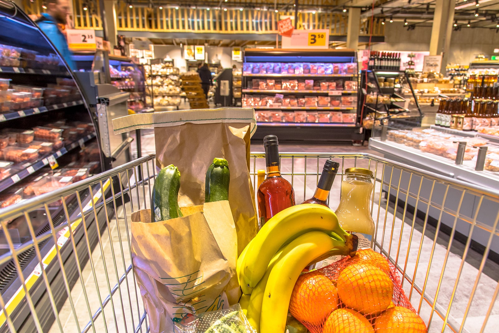Grocery cart in supermarket filled with food products seen from the customers point of view