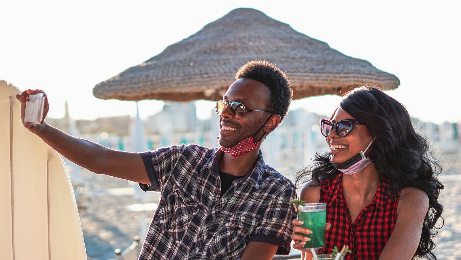 African American couple taking selfie with face mask on in beach bar