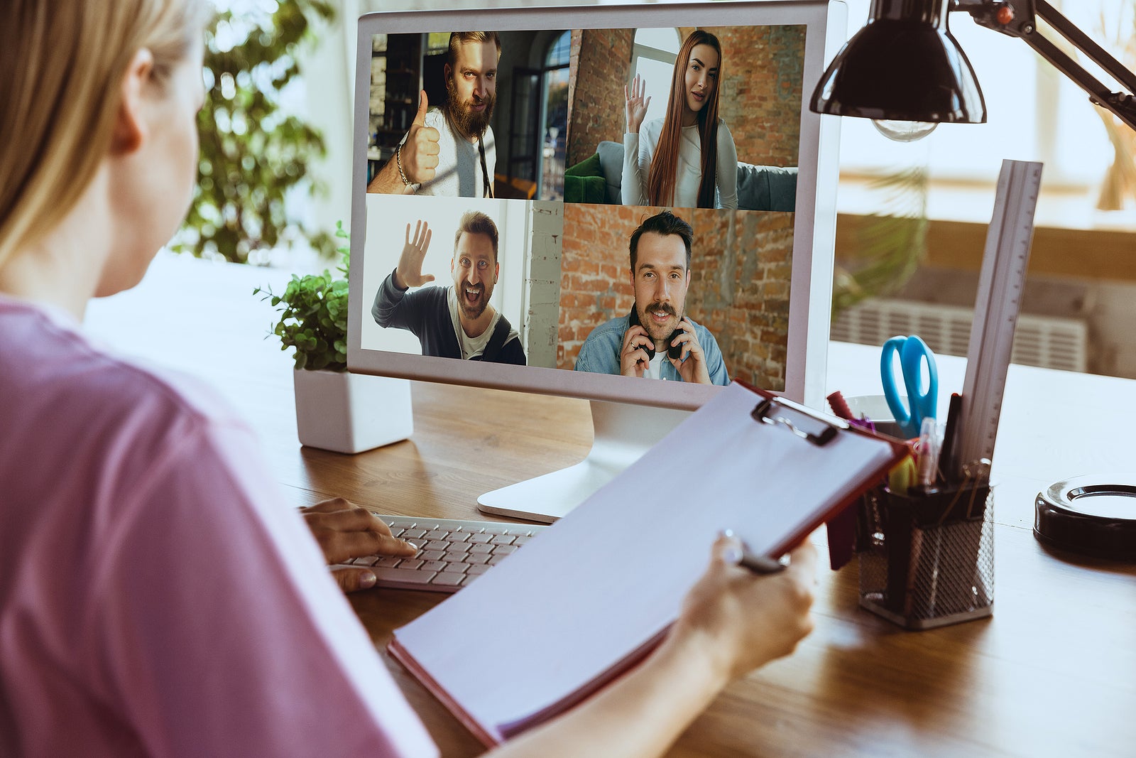 Remote meeting. Woman working from home during coronavirus or COVID-19 quarantine, remote office concept. Young boss, manager in front of monitor during online conference with colleagues and team.