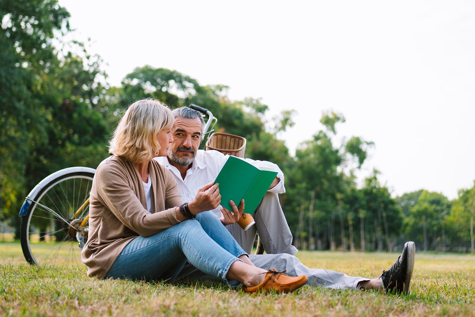 Caucasian elderly couple relaxing and sitting at the park reading the retirement plan to discussing together, happy marriage couple lifestyle, Worry free retirement insurance, love and cherish couple.