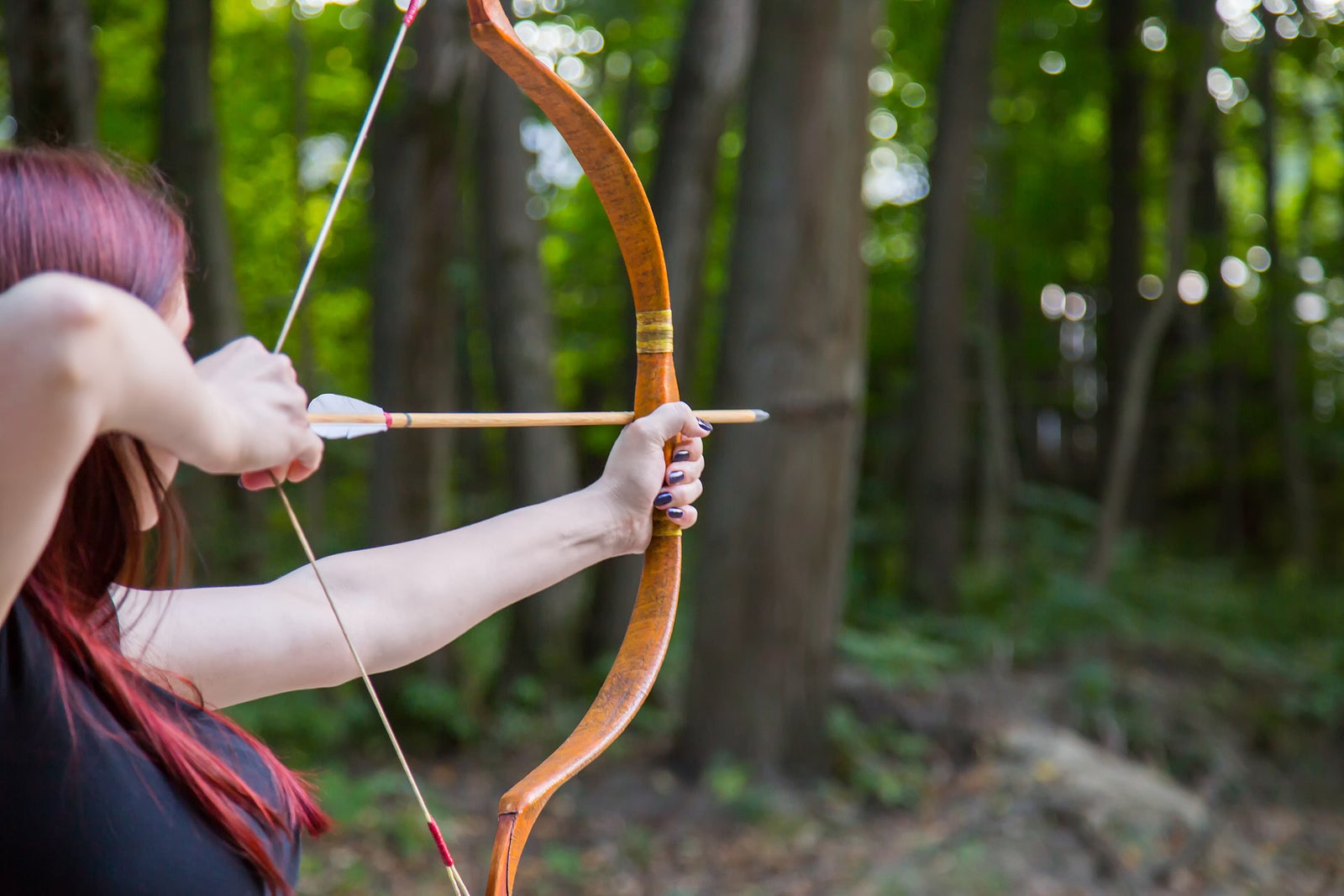 Woman archer shooting targets with wooden bow at historical festival. Archery and medieval culture concept