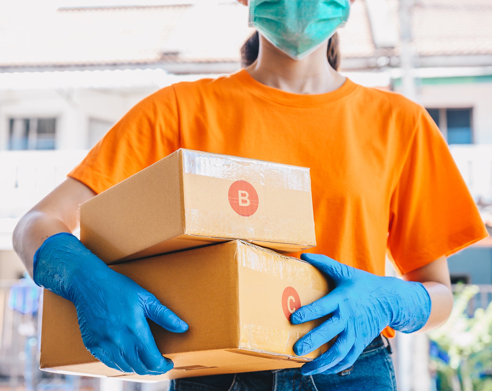 Delivery service courier holding boxes mail for sending to customer while wearing mask and glove for protect herself in covid-19 pandemic outbreak. Conceptual of hygiene service in covid-19 pandemic.