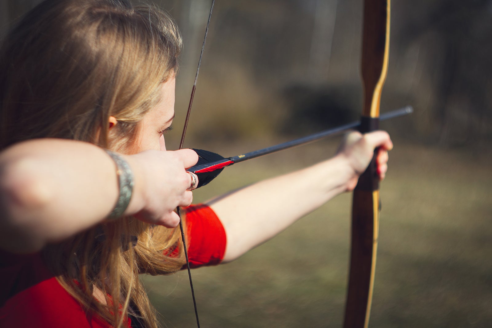 Girl dressed as a medieval teaching archery at the field