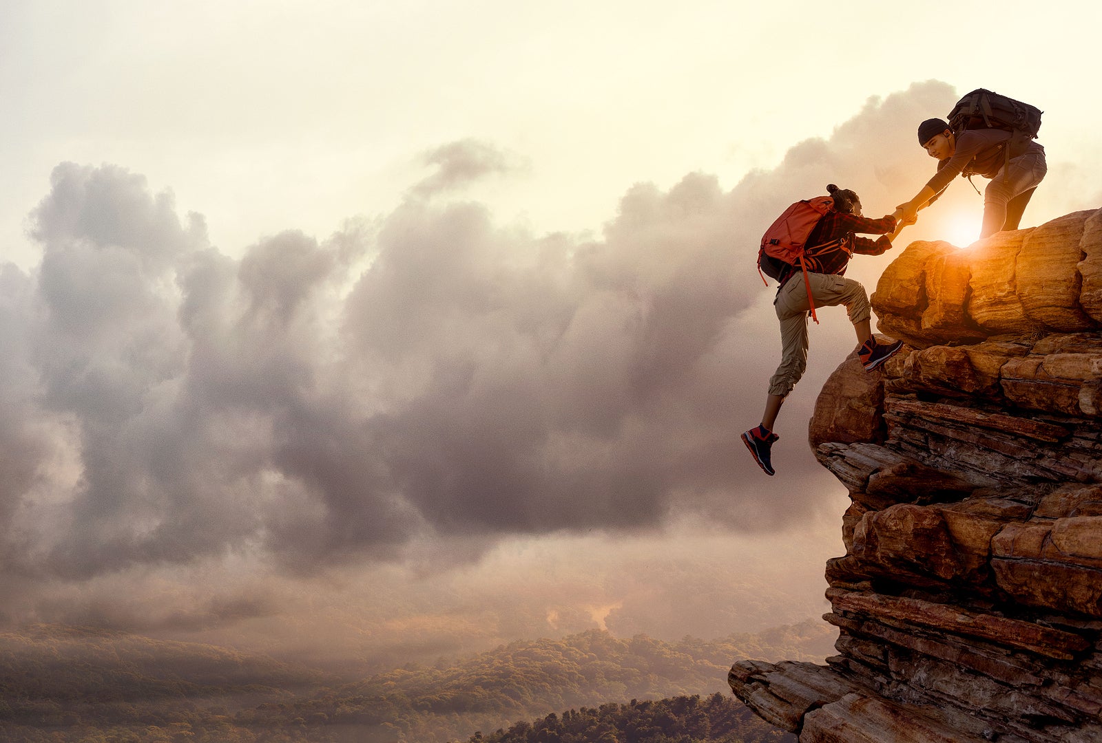 People helping each other hike up a mountain at sunrise. Giving a helping hand, and active fit lifestyle concept.Asia couple hiking help each other.