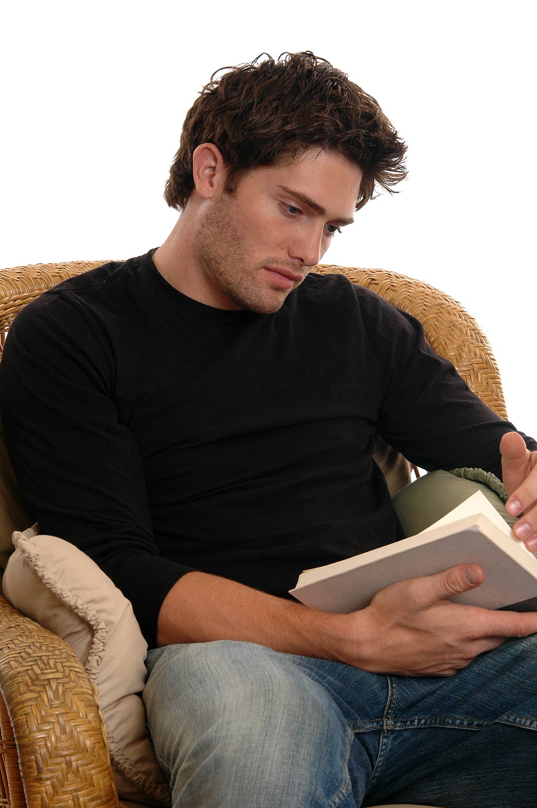 A handsome young man in a chair reading a book