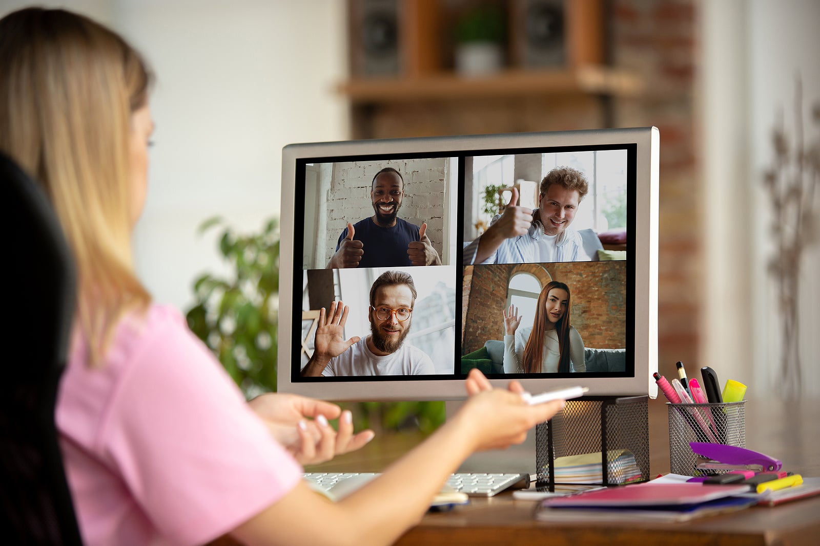 Remote meeting. Woman working from home during coronavirus or COVID-19 quarantine, remote office concept. Young boss, manager in front of monitor during online conference with colleagues and team.