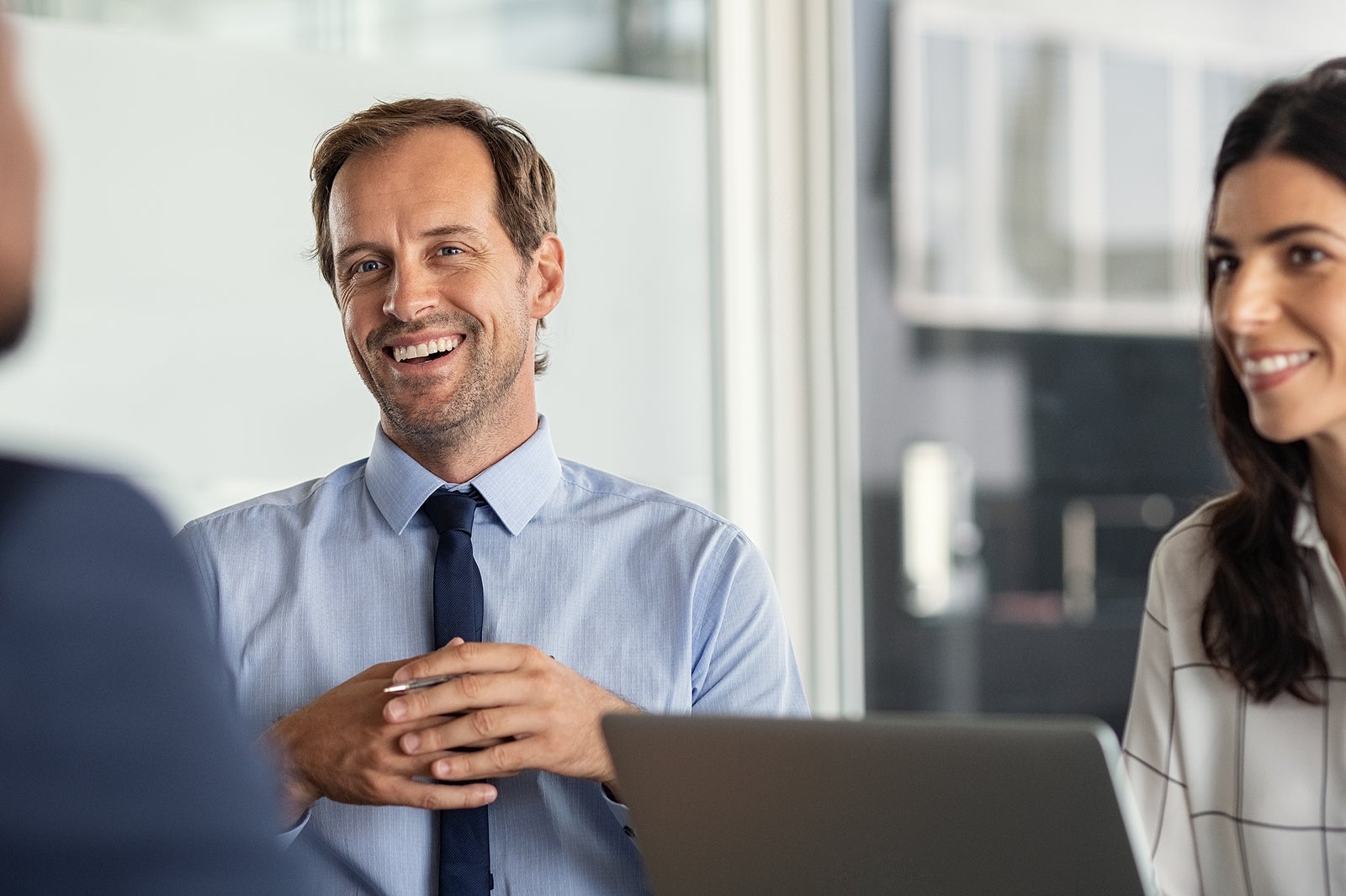 Business partners discussing ideas at meeting. Successful businessman listening to colleague during meeting in modern office. Happy mature business man and businesswoman smiling during brainstorming.