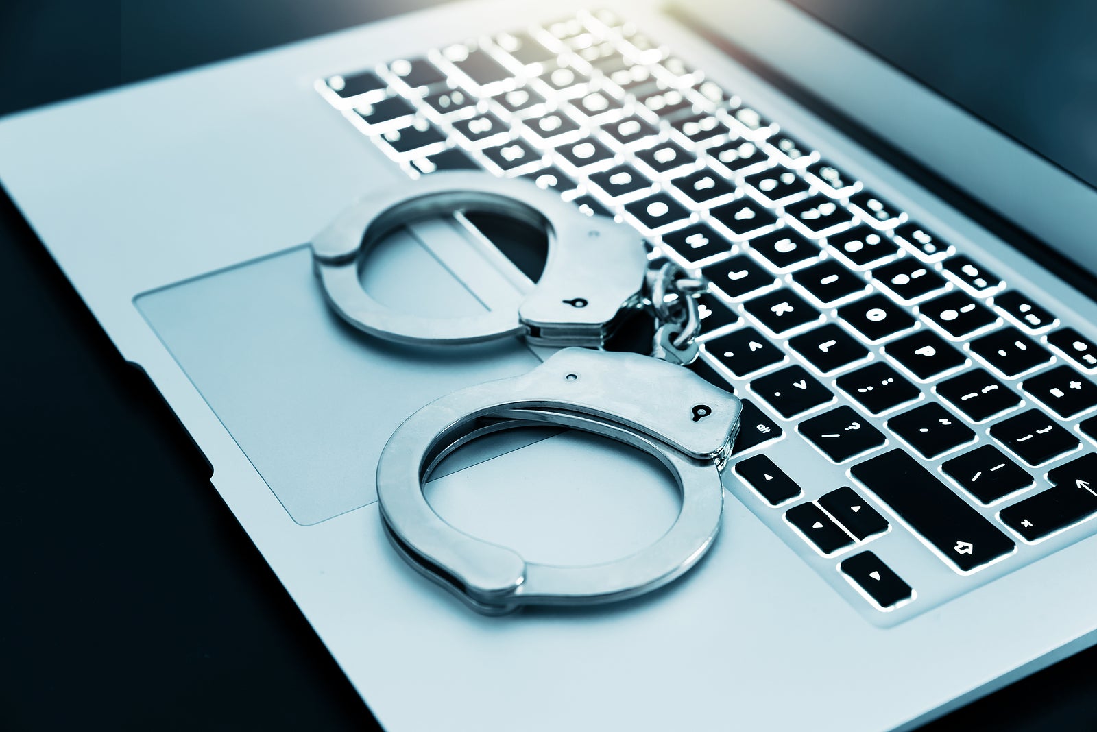 Internet crime concept. Handcuffs on the laptop keyboard, cyber crime concept