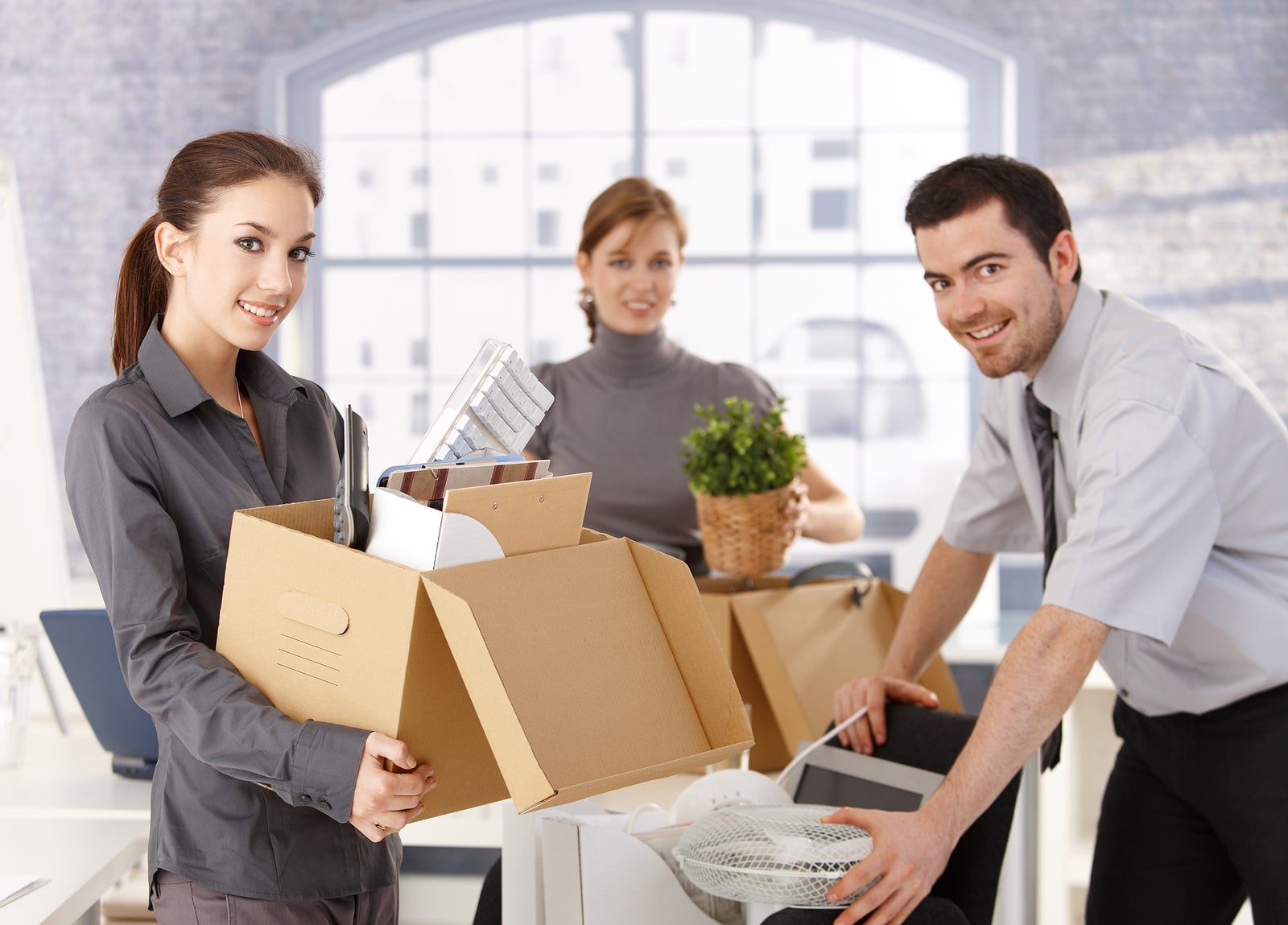 Young office workers moving office, unpacking boxes, smiling.?