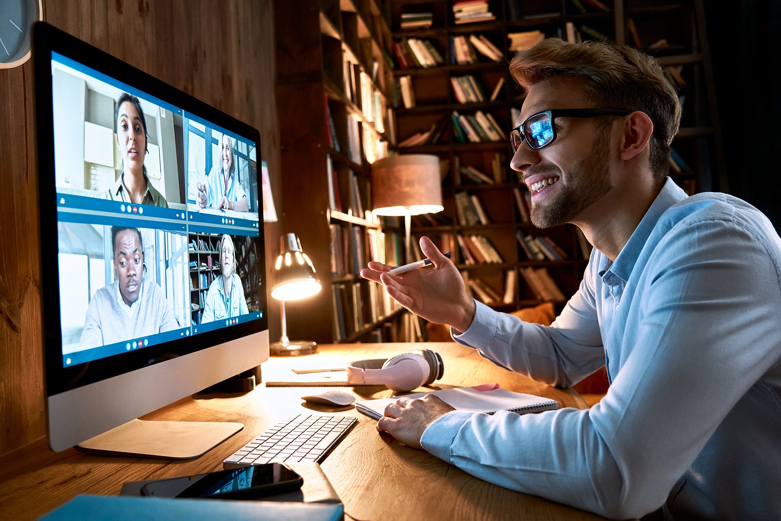 Business man having virtual team meeting on video conference call using computer. Social distance worker working from home office talking to diverse colleagues in remote videoconference online chat.