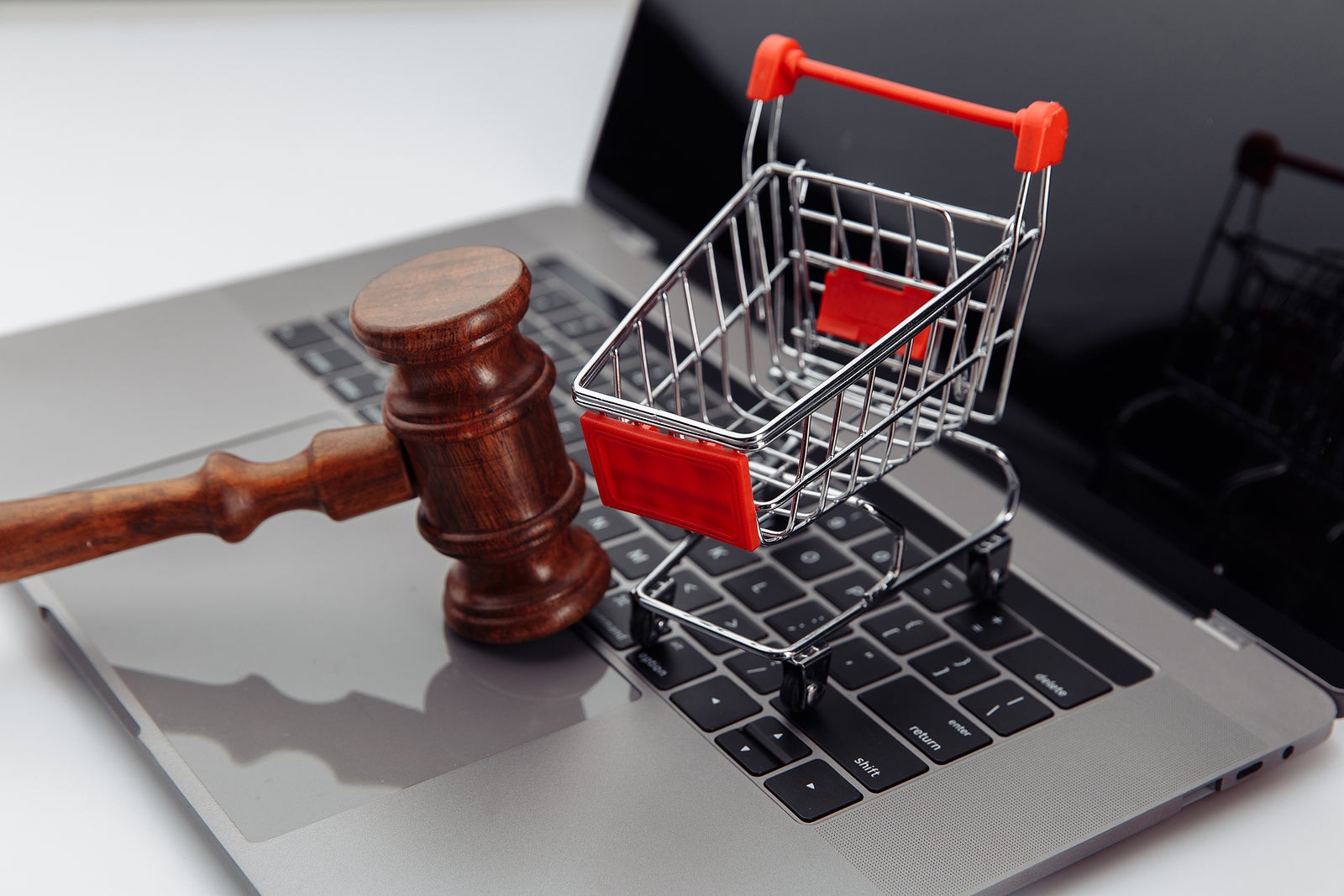 Laptop keyboard , shopping cart and auction hammer on table, online auction concept