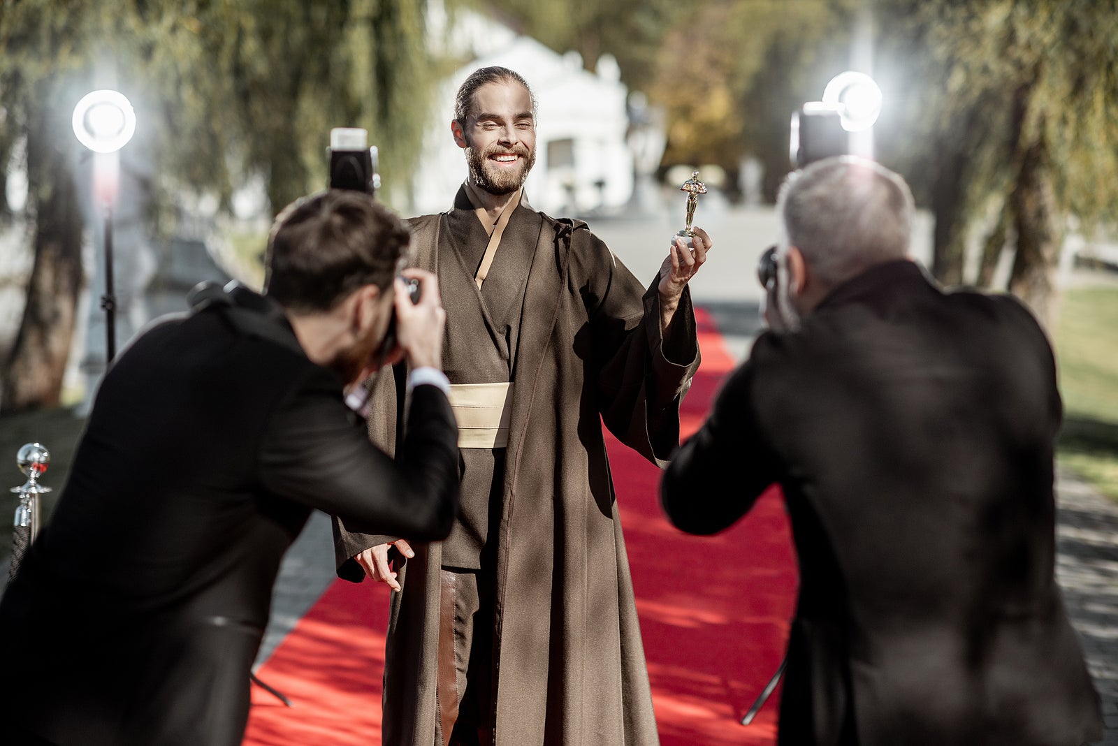 Man in costume as a well-known film character walking with annoying photo reporters on the red carpet during awards ceremony
