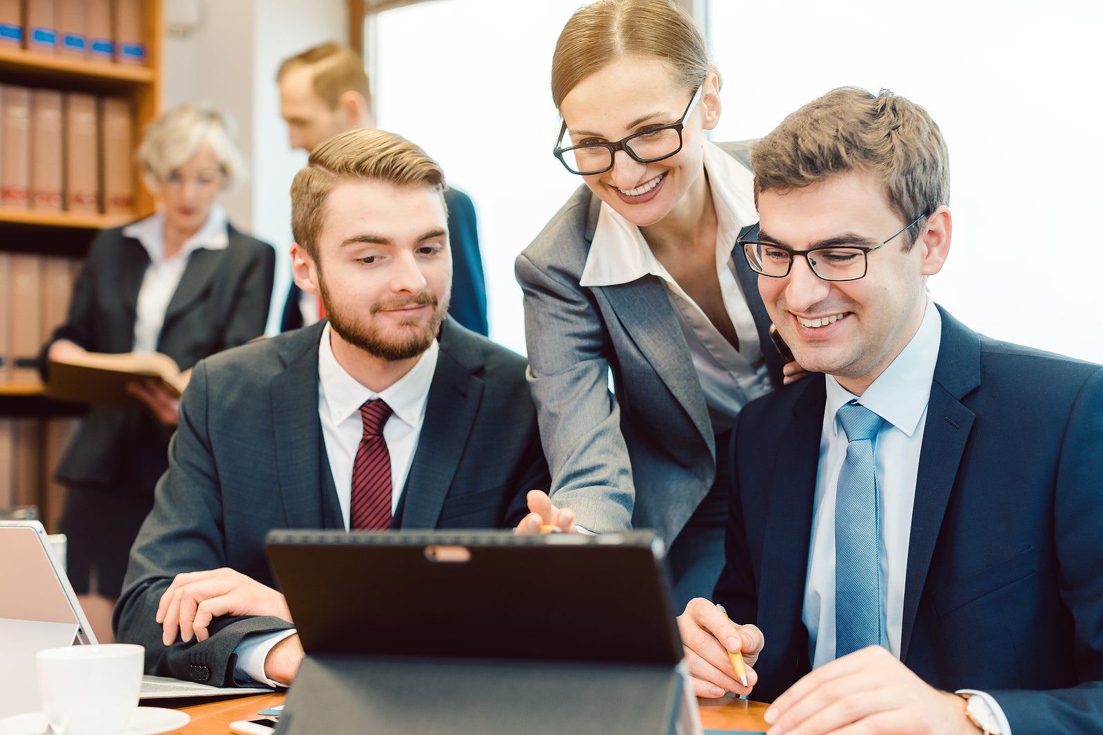 Young but diligent Lawyers in their law firm working on computer with books in background