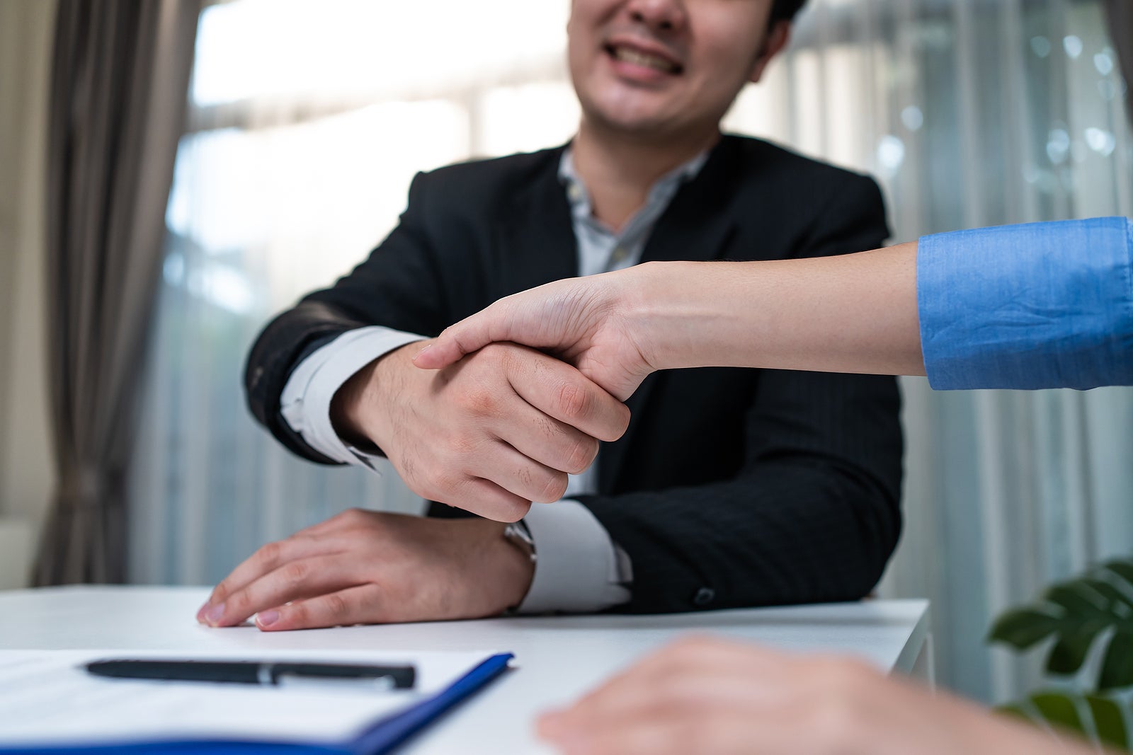 Close up hand of Salesman banker handshake with investor girl for loan insurance investment after negotiation for Business deal and acquisition. Businesswoman sign contract agreement on paper with pen