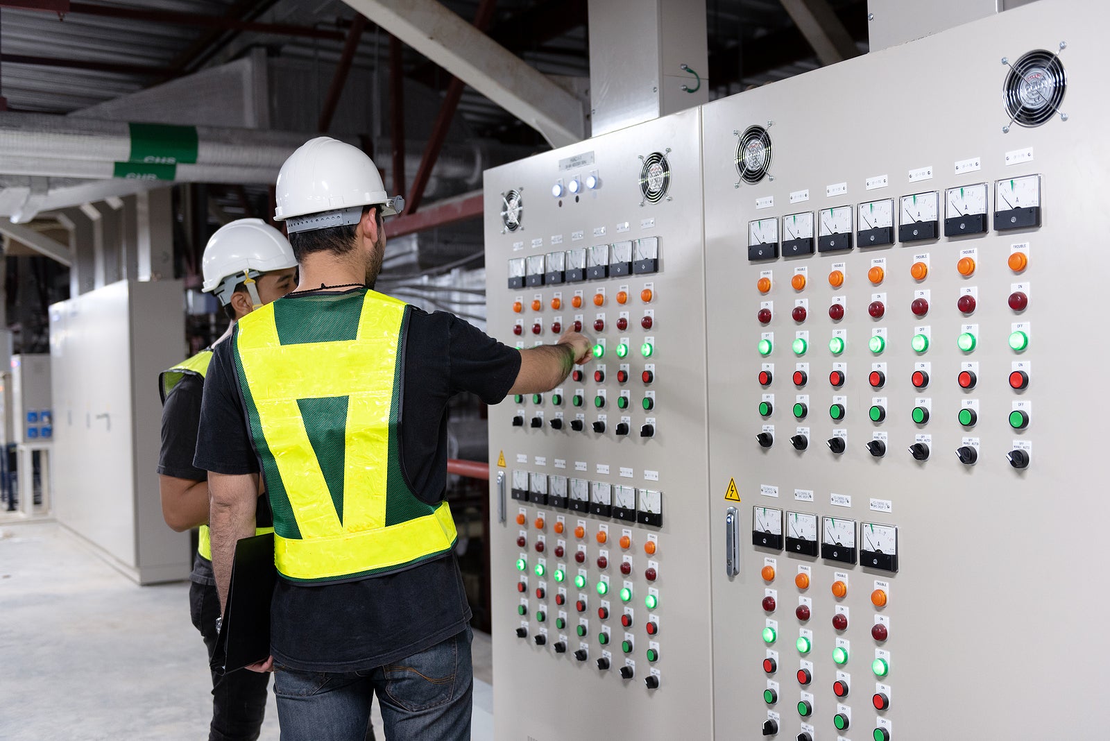 Electrical Engineer team working front HVAC control panels, Technician discussion and training daily check controls system for security functions in service room at factory.