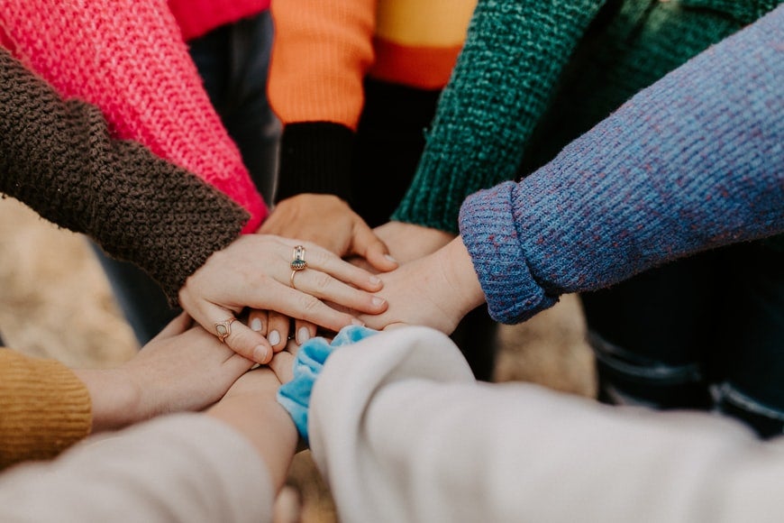 People on a team joining hands and working together