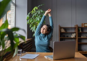 a happy business woman stretching at her desk