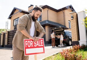 a man removing a for sale sign from a recently purchased house