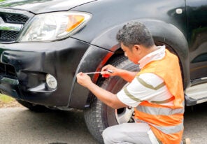 an insurance representative examining the damage to a company car