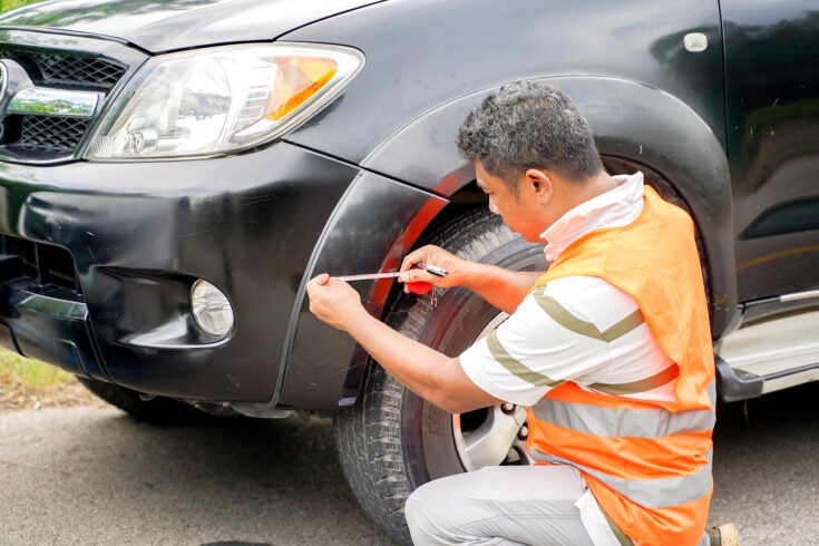 an insurance representative examining the damage to a company car