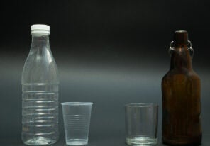 a plastic bottle and cup next to a glass bottle and cup
