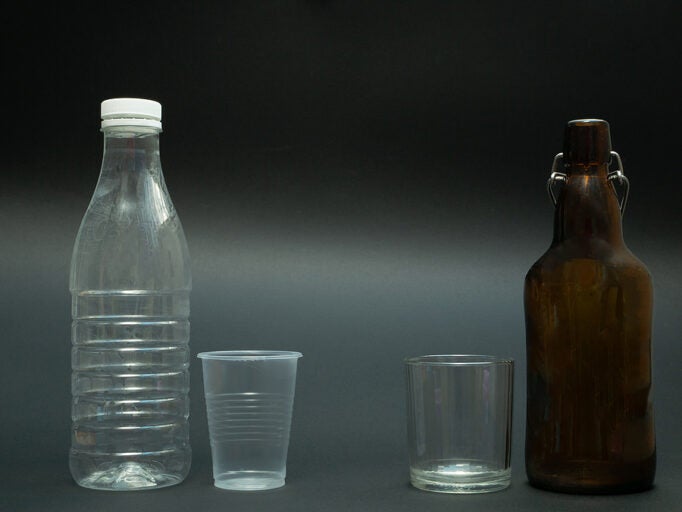 a plastic bottle and cup next to a glass bottle and cup