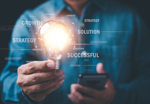 businessman holding a lit lightbulb