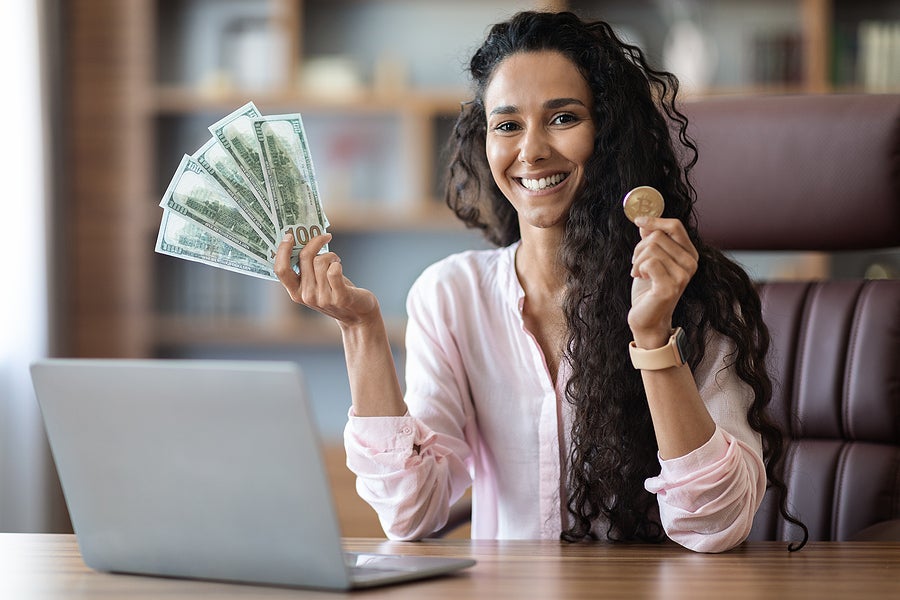 a crypto trader holding cash and a crypto coin