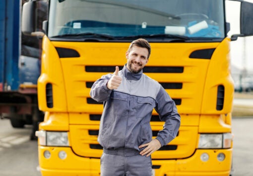 a commercial truck driver smiling and giving a thumbs up