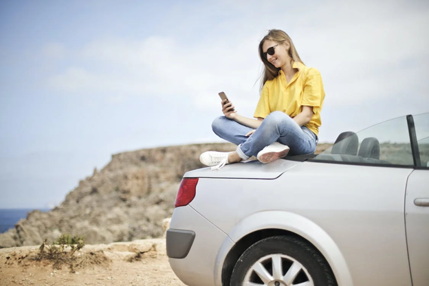 a woman enjoying the sun while sitting on her car