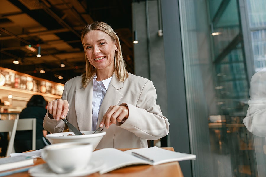 Smiling businesswoman is having a business lunch during working day in cafe. Blurred background
