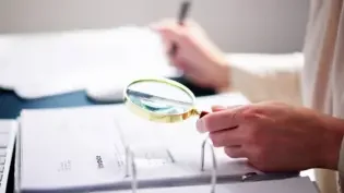 an auditor closely inspecting an invoice