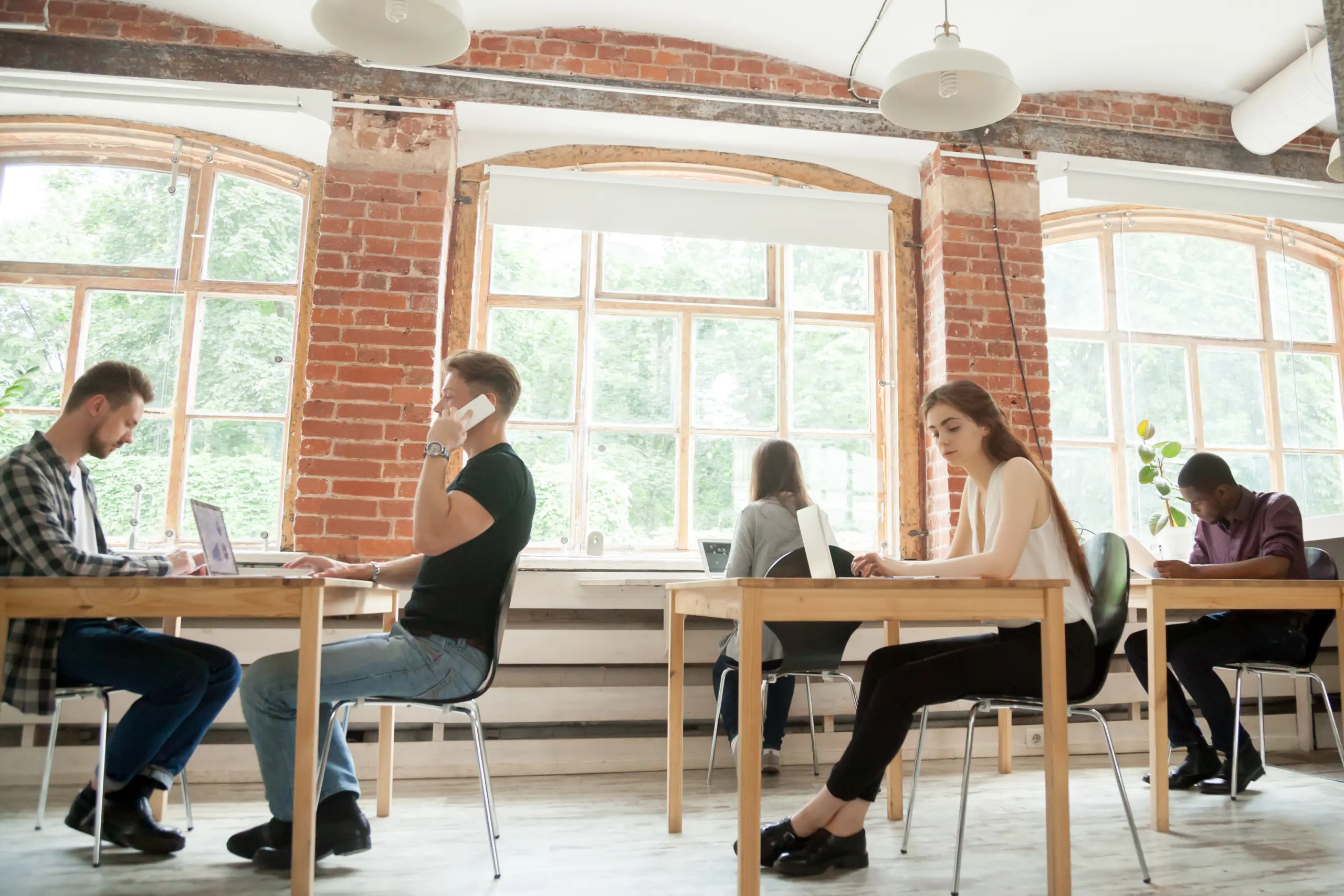 Co-working space concept, diverse people employees working in shared office together, multiracial business men and women sitting at desks using devices in modern loft new coworking interior