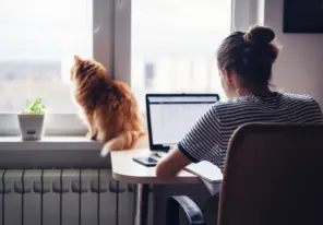 a woman working next to her cat in her home office