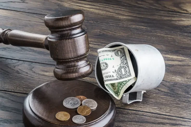 a law gavel and a dollar bill emphasizing the financial burdens of lawsuits