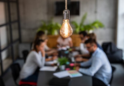 a lightbulb above a meeting emphasizing bright ideas in business