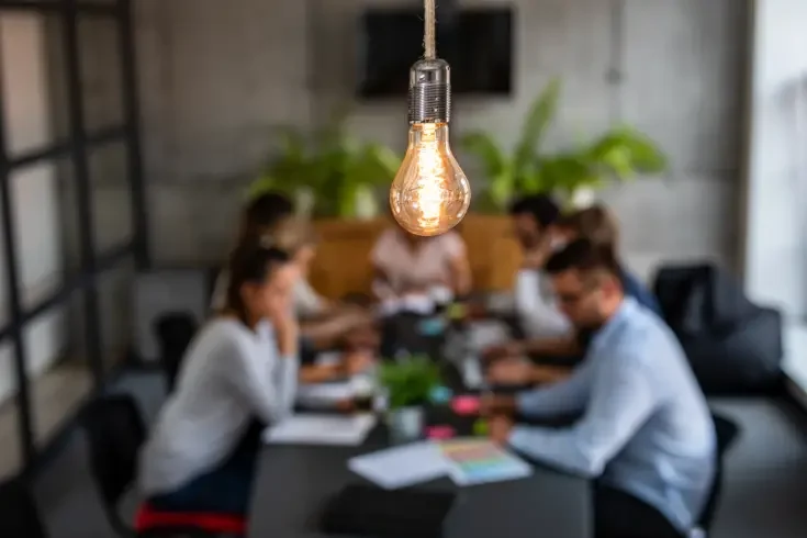 a lightbulb above a meeting emphasizing bright ideas in business